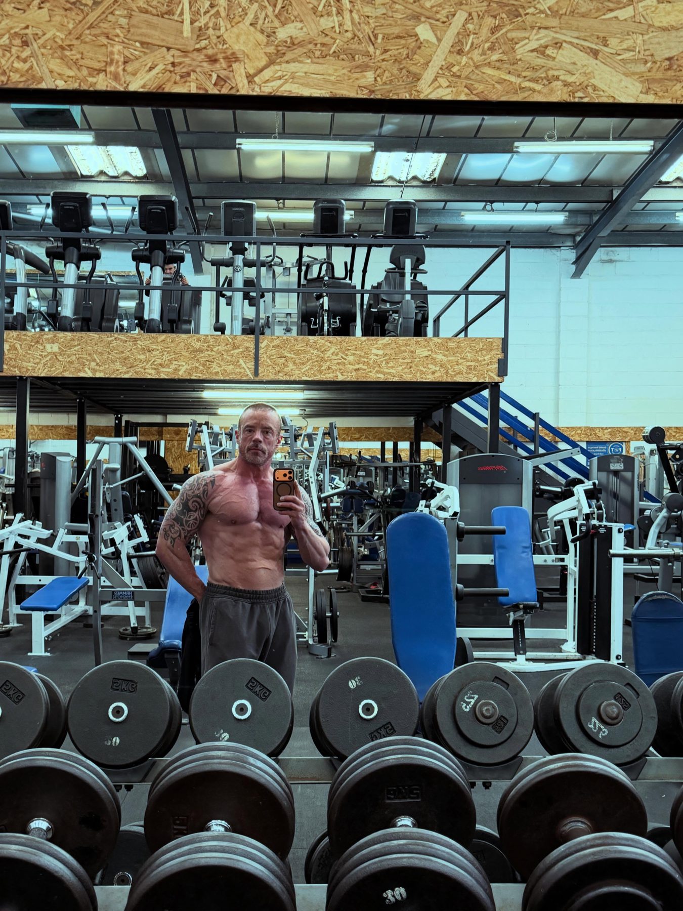 Rows of dumbbell racks on the gym floor at Pro Strength & Fitness, with the upstairs mezzanine above